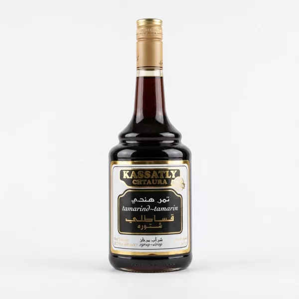 A 600ml glass bottle of Kassatly Chtaura Tamarind Syrup with its black and gold label, containing a dark amber liquid and sealed with a gold screw cap, isolated on a plain white background.