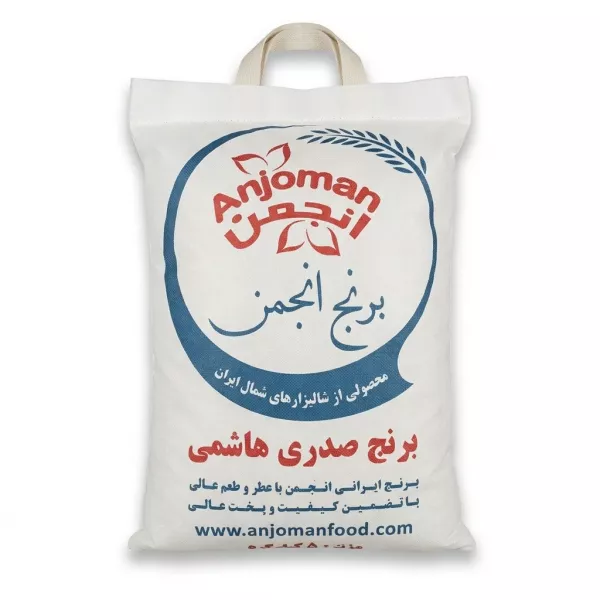 A centered, front-view professional studio photograph of a 5kg fabric bag of Anjoman Sadri Hashemi Rice. The white fabric bag features the 'Anjoman' logo in red within a circular motif, the product name in large blue and red Persian script ('برنج انجمن' and 'برنج صدری هاشمی'), descriptive Persian text regarding quality and origin, and the website 'www.anjomanfood.com'. The bag has a woven handle and sits on a pure white background with soft, even shadowing.
