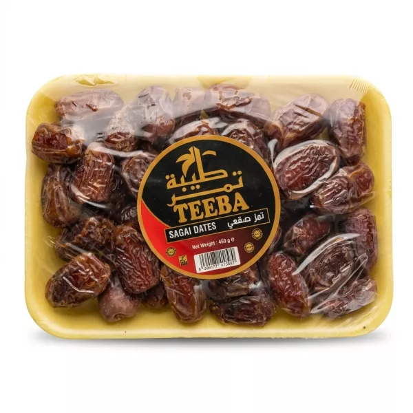 Hand holding a tray of Teeba Sagai Dates in a yellow pack inside a grocery store