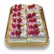 Selection of bright berry delight cake slices topped with strawberries, raspberries, whipped cream and crushed pistachios on a golden tray