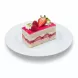 Single slice of Mixed Berry Celebration Cake on white plate topped with strawberries, raspberries and pistachios