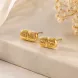 14K gold plated Daily Dosage Pill Stud Earrings displayed on a minimalist marble surface, showcasing the polished capsule design engraved with "Daily Dose".