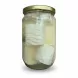 Side view of white cheese pieces immersed in clear brine in jar