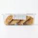 A clear plastic container of baked pastries, as seen in a side view. The label, with all its original text and data, is cleanly displayed and perfectly legible, centered on the front of the packaging. The four maamoul cookies are clearly visible through the plastic against a pure white background with soft, even studio lighting.