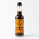 A 150ml glass bottle of Lea & Perrins Worcestershire Sauce, featuring its distinctive orange and yellow label, is held in a person's hand against a clean white studio background. The bottle is well-lit with soft shadows, highlighting the dark, matured sauce inside. PRODUCT TITLE: Lea & Perrins Worcestershire Sauce - Authentic Matured 150ml