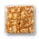 A top-down view of an unopened square plastic tray containing four pre-cut squares of golden-brown, flaky Yayla potato pastry (su böreği) against a white background.